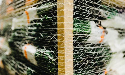 Een close up foto van een pallet met dozen die door een wikkelnet en hoekprofielen bij elkaar wordt gehouden. 