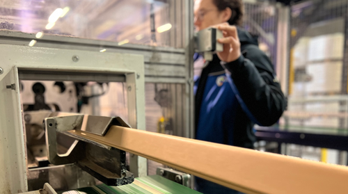 Een productiemedewerker die bij een hoekprofielmachine staat te werken.